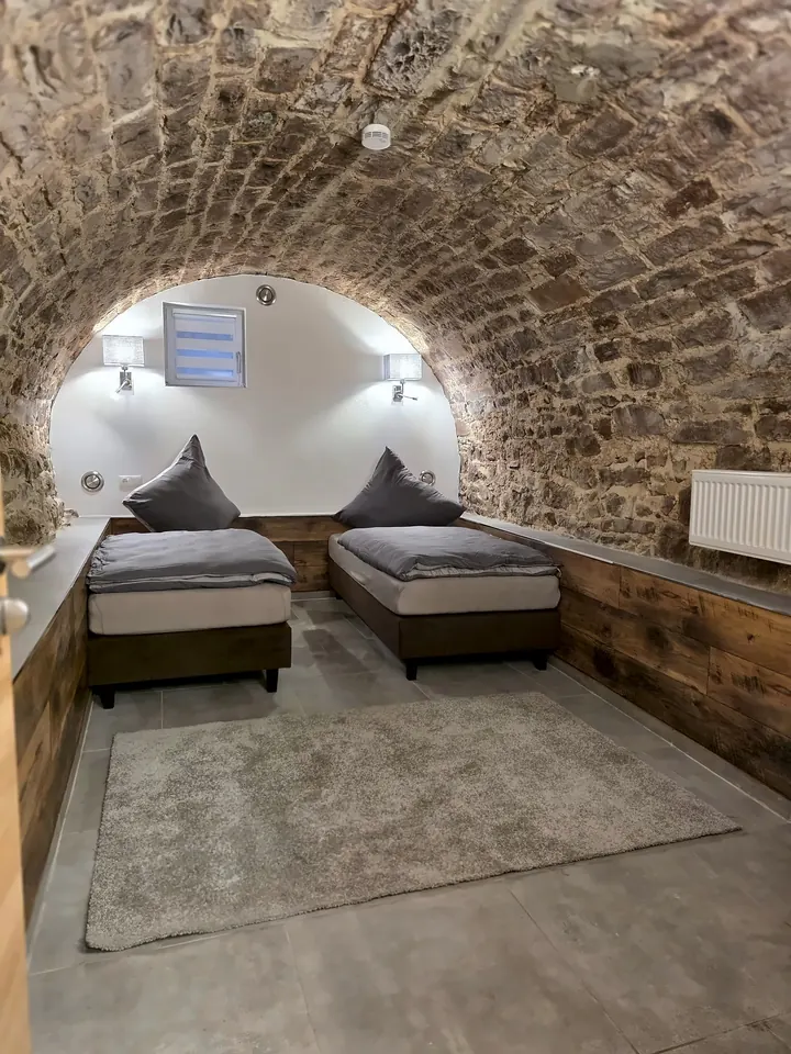 Schlafzimmer unter einem Gewölbe aus Bruchstein mit zwei Betten