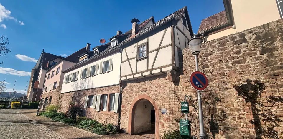 Blick die Gasse entlang auf das Haus mit Torbogen und Stadtmauer